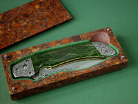 "Procyon" liner lock folding knife, obverse side view,in hand-engraved ATS-34 high molybdenum stainless steel blade, hand-engraved 304 stainless steel bolsters, anodized 6AL4V titanium liners and lockplate, Pounamu New Zealand Greenstone Nephrite Jade gemstone handle, case of Granite, Quartz Terrazzo composite